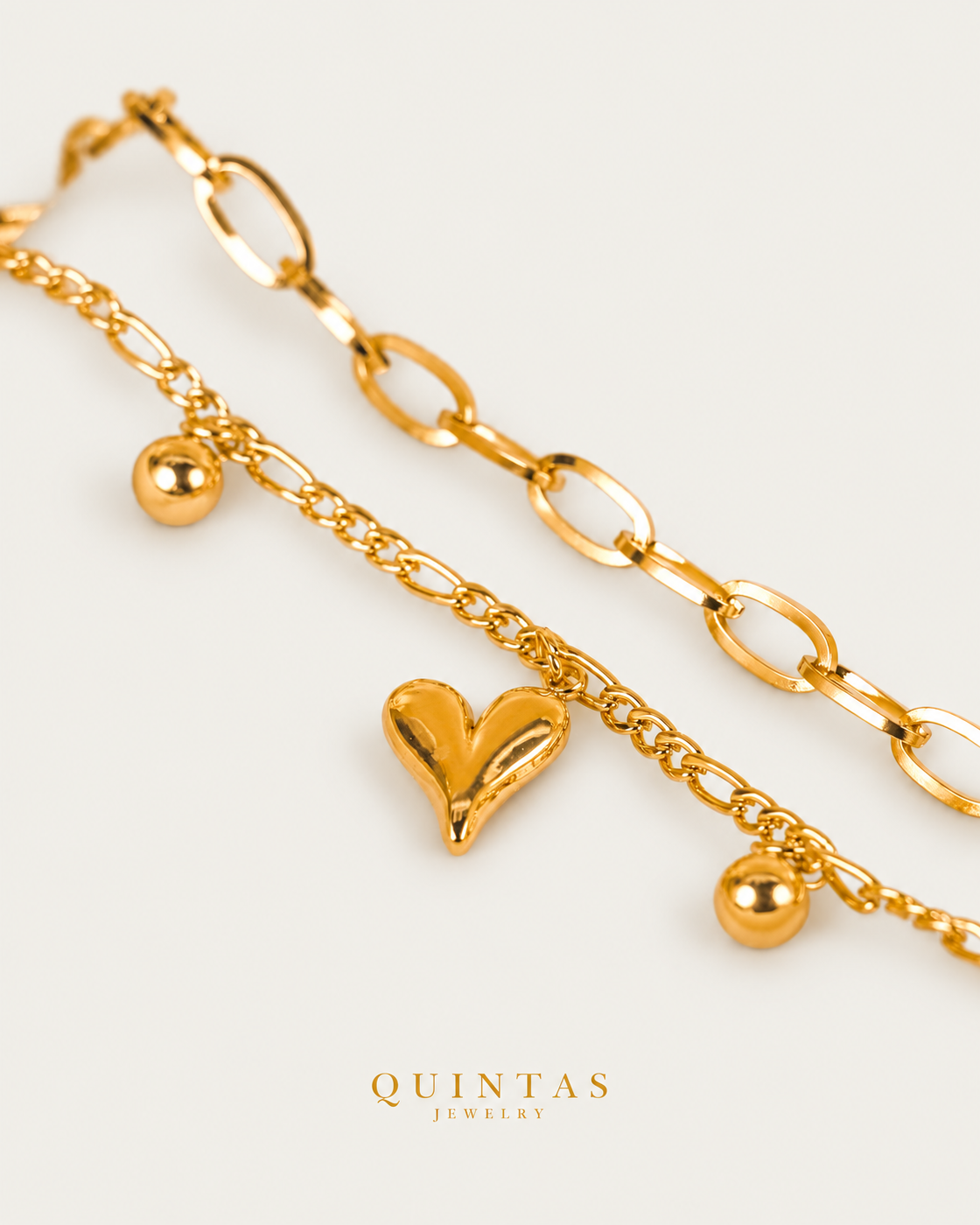 Juliette Heart Charm Bracelet — gold bracelet, genuine oblique detail, neutral greige background
