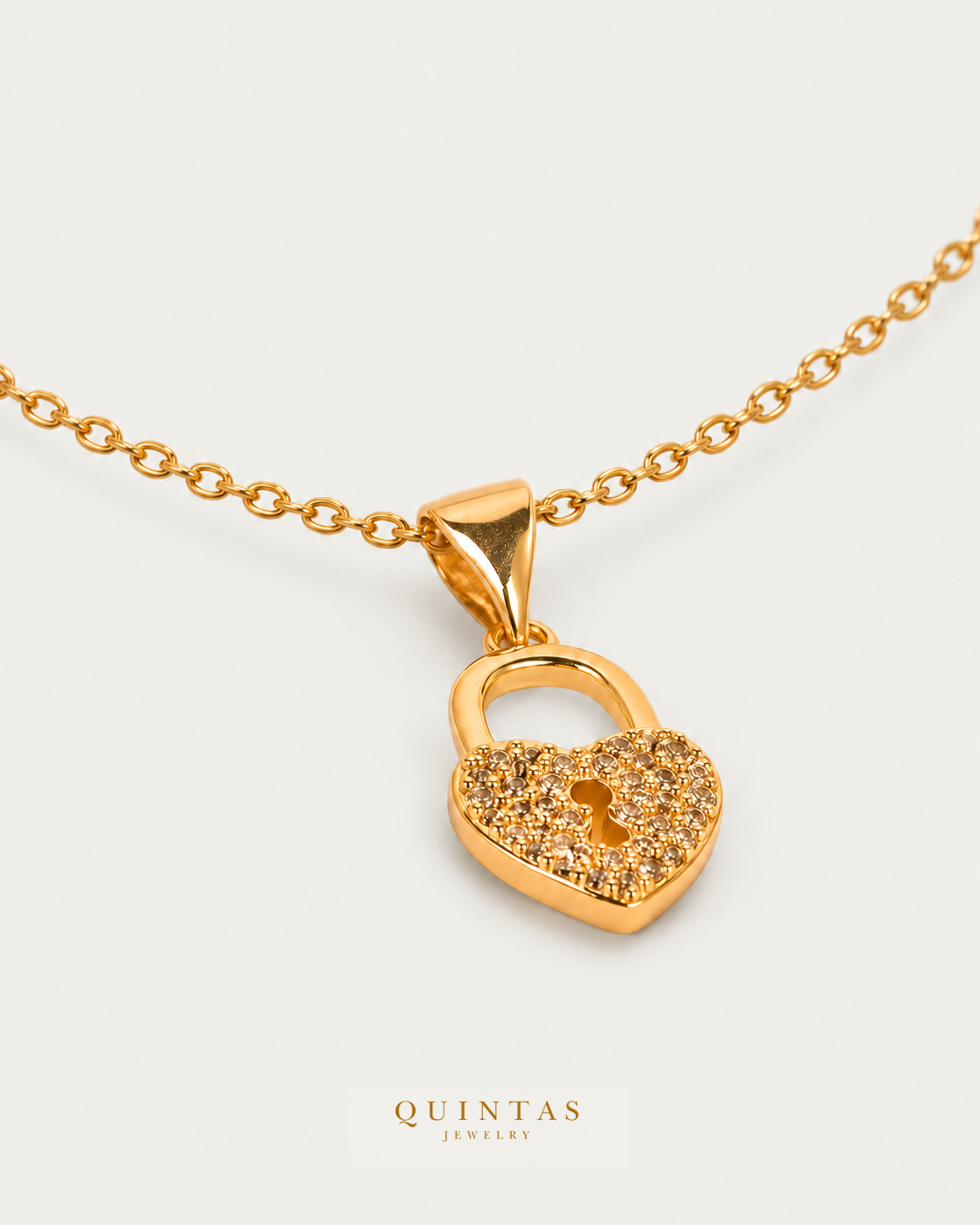 Amara Heart Lock Necklace — source-verified cable oblique view, off-white background, canonical gold logo