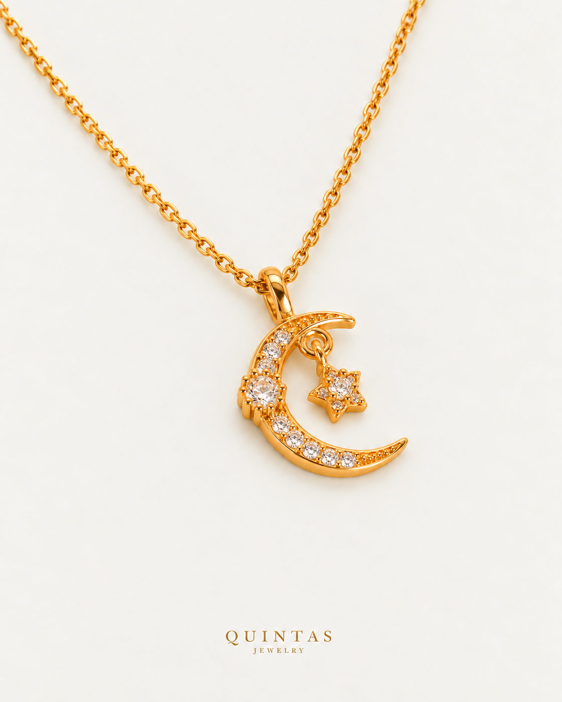 Luna Moon and Star Necklace cable chain companion photographed angle on neutral greige; canonical Quintas Jewelry logo