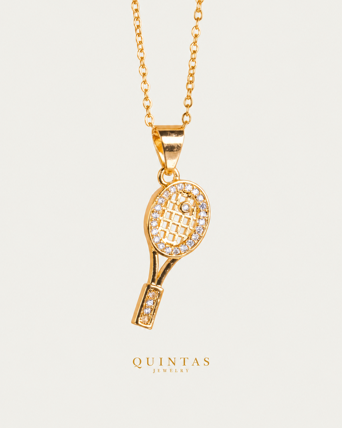 Golden Tennis Racket Necklace — gold cable chain, frontal hero, neutral greige