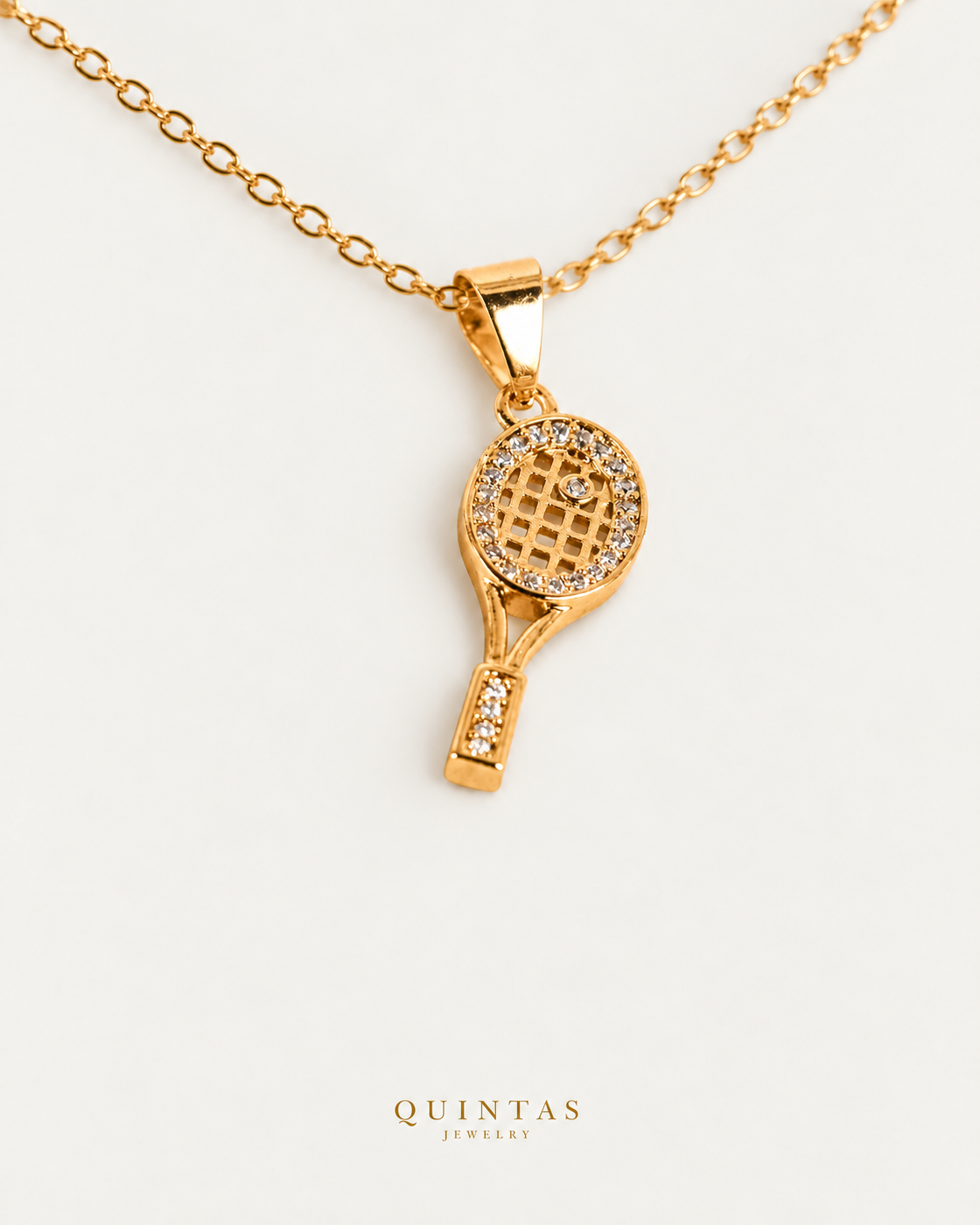 Golden Tennis Racket Necklace — gold cable chain, companion view, canonical Quintas logo