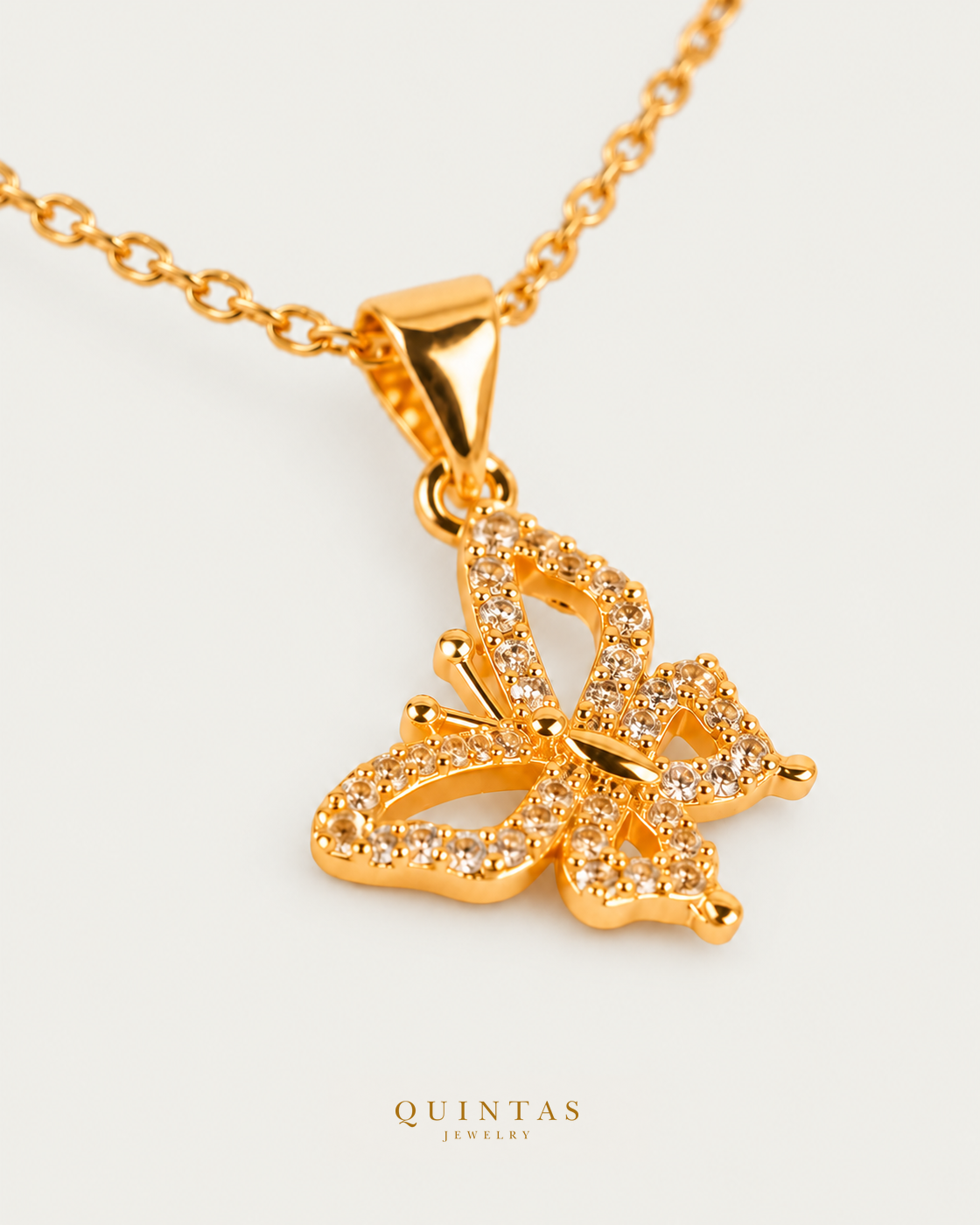 Iris Butterfly — cable chain, genuine oblique detail, neutral greige background; canonical Quintas Jewelry logo