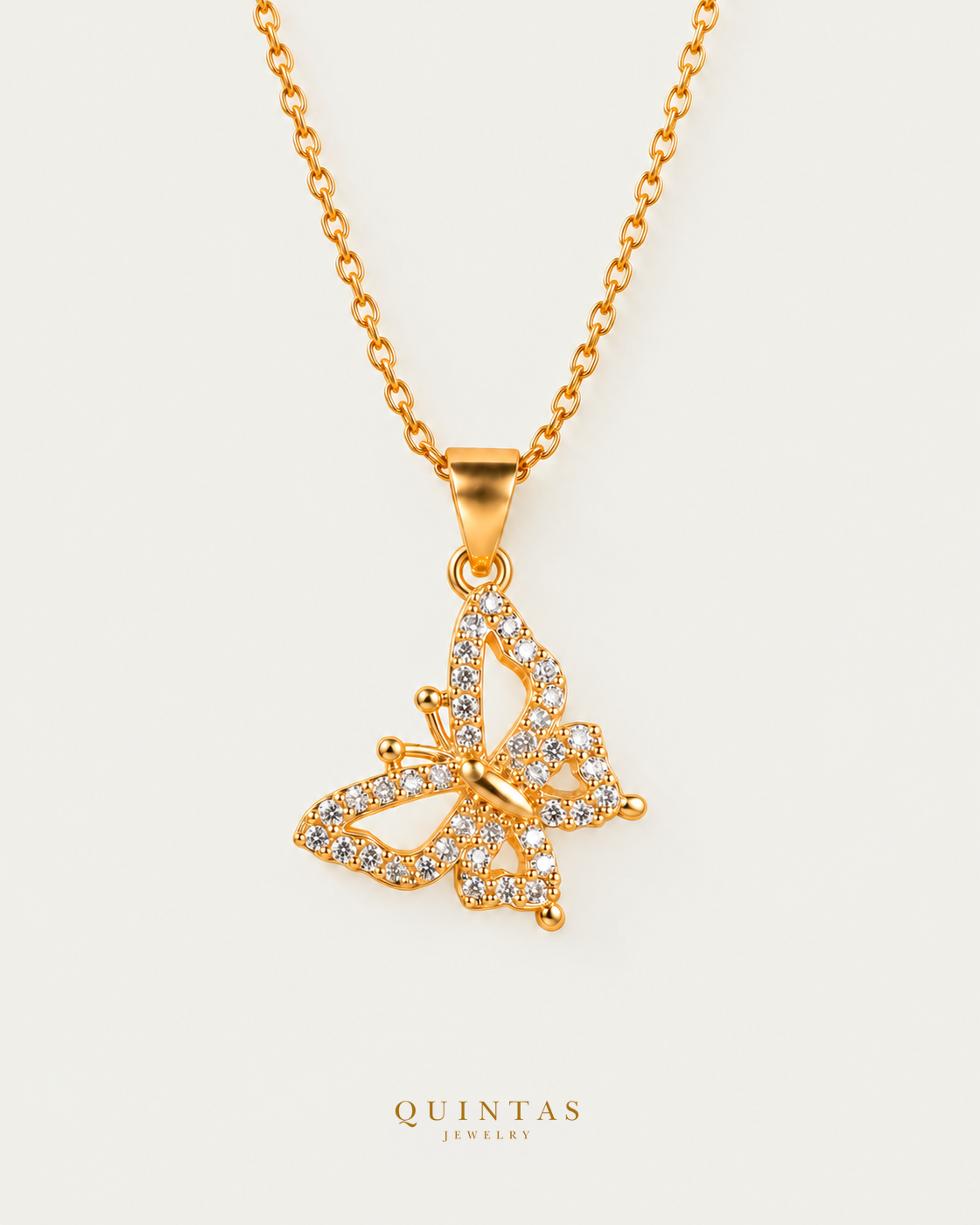 Iris Butterfly Necklace — gold cable chain, neutral greige; canonical Quintas Jewelry logo