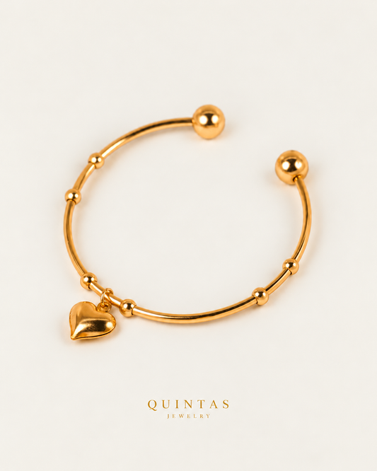 Aurora Heart Bangle Bracelet in gold, near-overhead view on neutral greige
