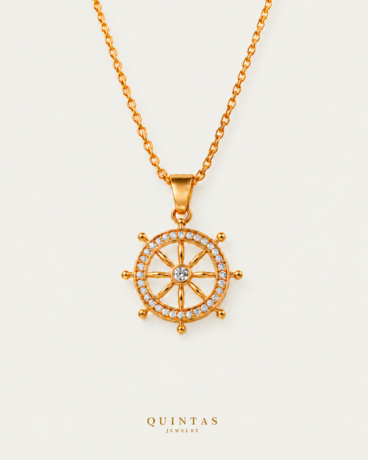 Ship's Wheel Necklace on gold cable chain on a neutral greige background with a faint soft shadow