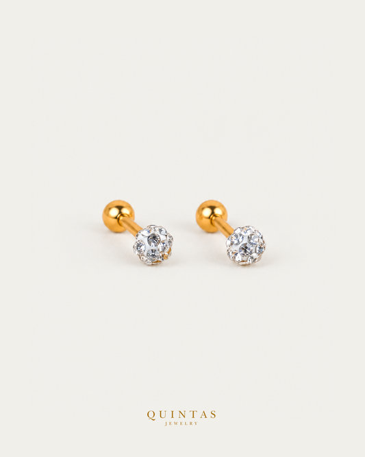 Stardust earrings with visible gold stems and spherical backs on neutral greige background