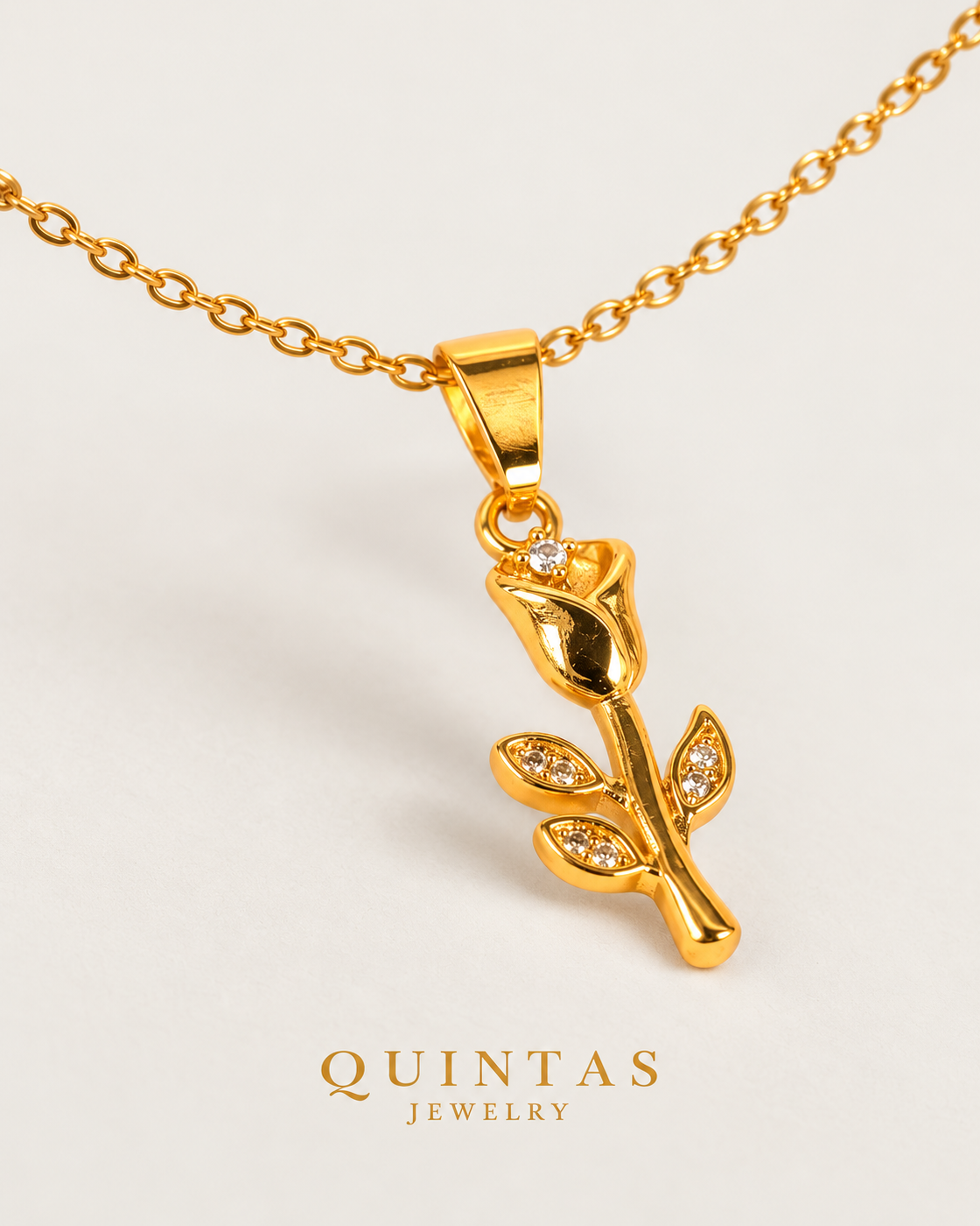 Aurora Tulip Necklace — gold cable chain, lying oblique view, neutral greige