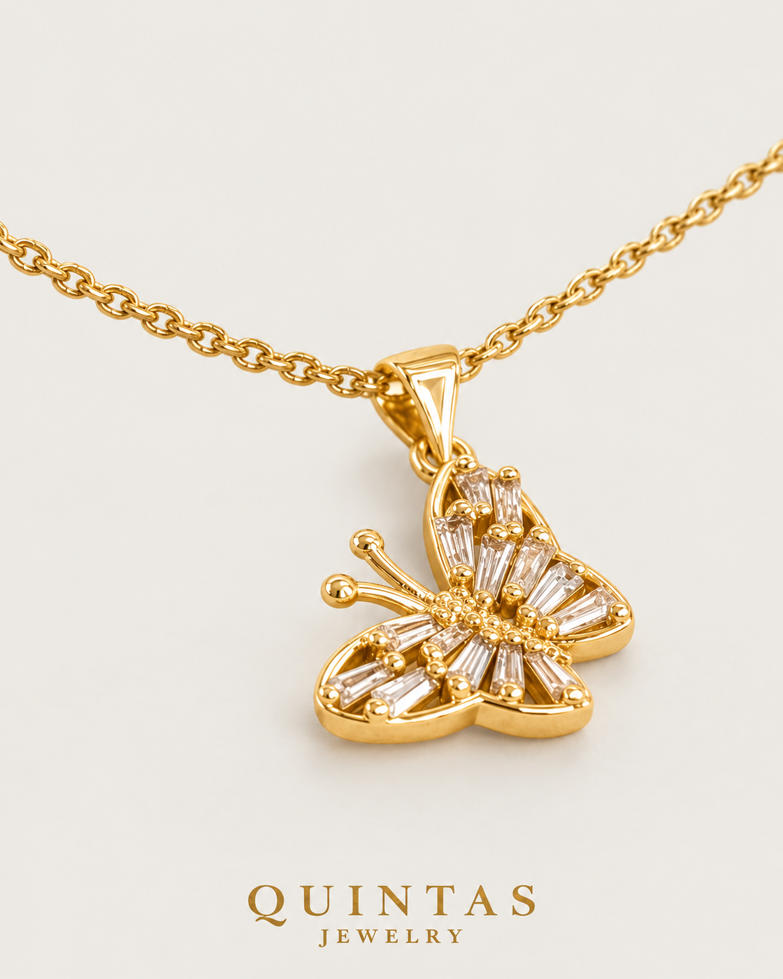 Glass Butterfly Necklace — gold cable chain, lying oblique view, neutral greige